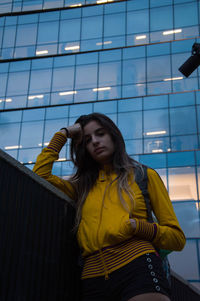 Beautiful young woman standing against building