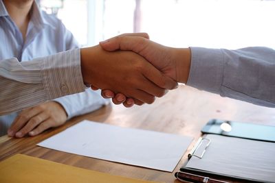 Cropped image of judge handshaking with client at desk