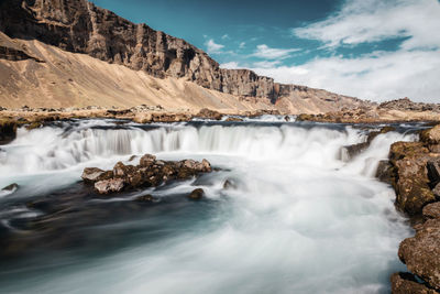 Scenic view of waterfall against sky