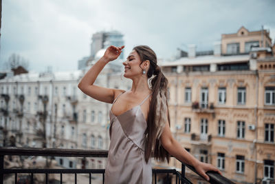 Young woman wearing sunglasses standing against railing in city