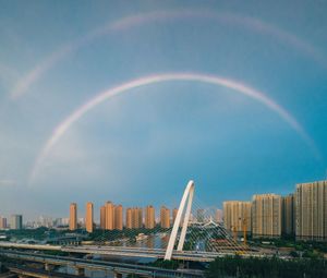 Rainbow over buildings in city against sky