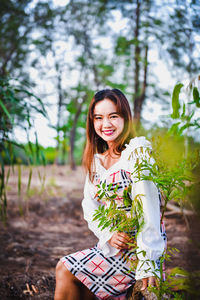 Portrait of smiling young woman sitting on land