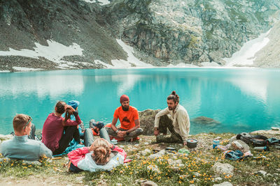 People sitting on rocks by lake