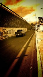 Cars on road against sky during sunset