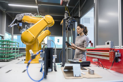 Businesswoman checking industrial robot in high tech company