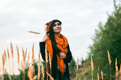 Woman standing amidst plants against sky