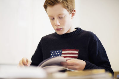 High school boy reading book in classroom