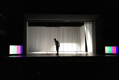 Full length of man walking in illuminated corridor