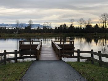 Empty pier over lake against sky