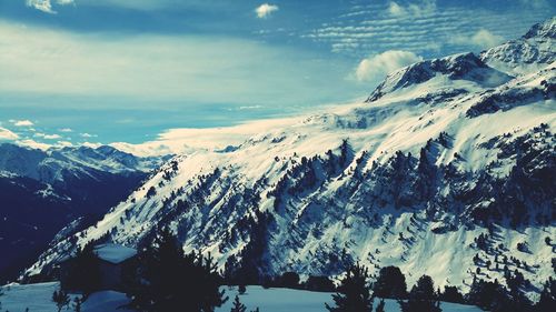 Scenic view of snow covered mountains against blue sky