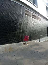 Rear view of person walking on footpath against building