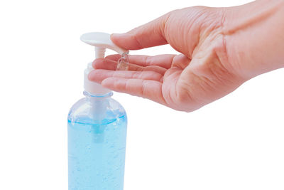 Close-up of hand holding bottle against white background