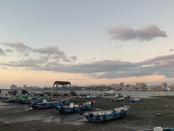 Boats moored in harbor at sunset