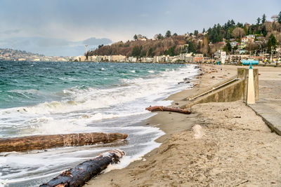 A view of alki beach in west seattle, washington with condos and sea wall on a windy day.