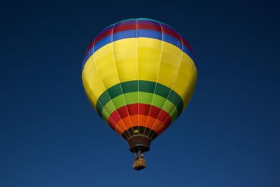 Low angle view of hot air balloon flying against clear blue sky