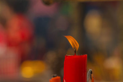 Close-up of red burning candles on cutting board