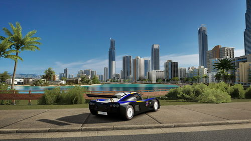 Cars on city street by buildings against sky