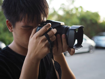 Close-up of teenage boy photographing with camera while standing on road