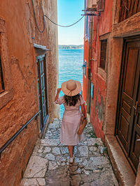 Woman from behind. standing in ally of old town by sea.