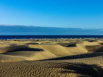 Scenic view of beach against clear blue sky