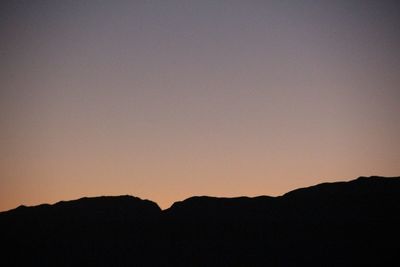 Scenic view of silhouette mountains against clear sky at sunset