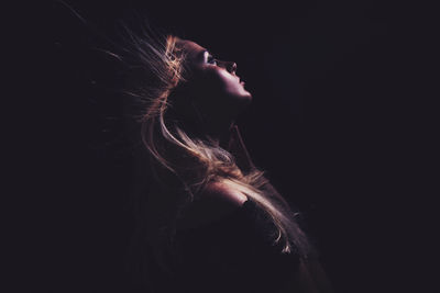 Close-up of young woman against black background