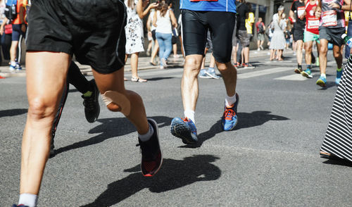 Low section of athletes running on road in city