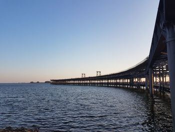 Bridge over calm sea against clear sky