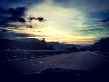 Cars on road against sky during sunset