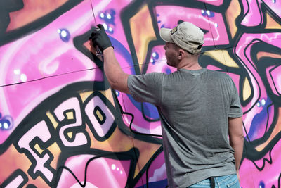 Portrait of young woman standing against graffiti wall