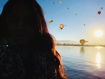 Rear view of woman at beach against sky during sunset