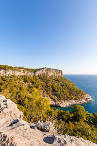 Big rock with forest and azure sea in summer