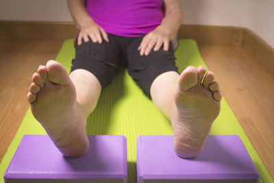 Low section of woman relaxing on exercising mat