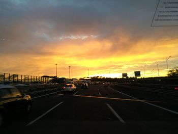 Cars on road against sky during sunset