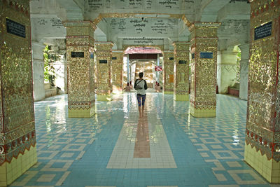 Rear view of woman standing by swimming pool against buildings