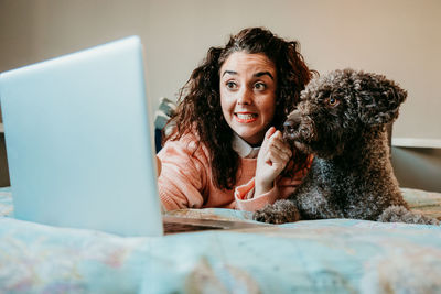 Portrait of young woman using smart phone while sitting on bed