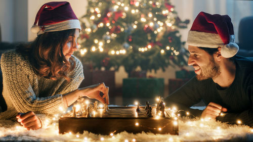 Couple plays chess at christmas on white carpet