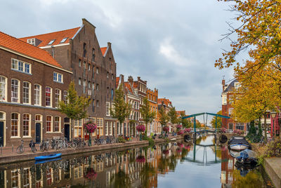 Arch bridge over canal amidst buildings against sky