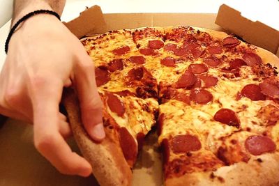 Close-up of hand holding pizza