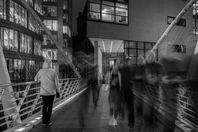 Rear view of woman standing by railing against built structure in city at night