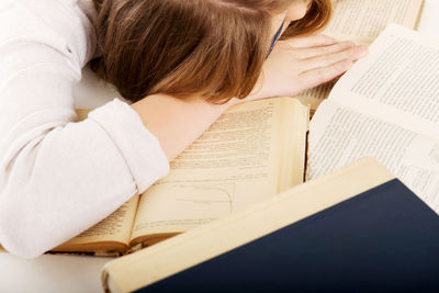 High angle view of woman sleeping on books at table