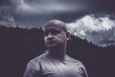 Close-up of mature man against mountain and cloudy sky