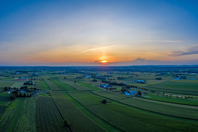 Scenic view of agricultural field against sky during sunset