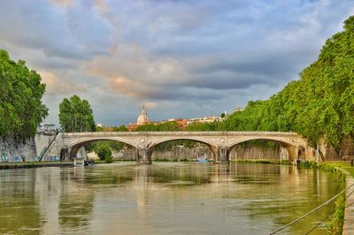 Arch bridge over river against sky