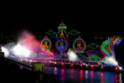 Illuminated building by river at night