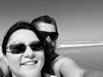 Portrait of smiling couple at beach against sky