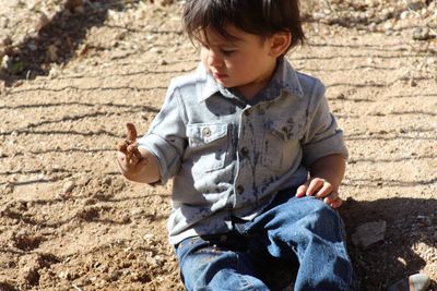 Boy playing with mud on sunny day