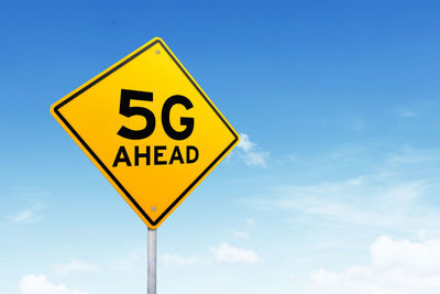 Low angle view of road sign against blue sky