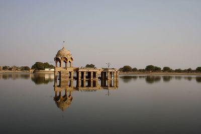 Reflection of temple in lake against clear sky