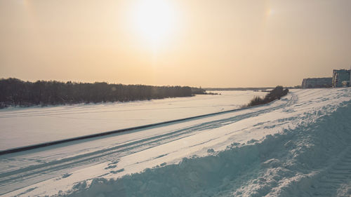 Scenic view of snow covered land against sky during sunset